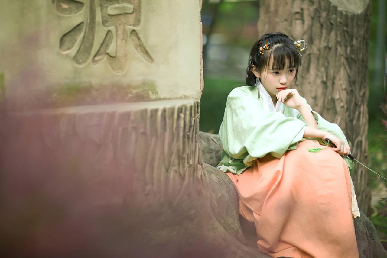 修老虎坐在树干旁，轻抵下巴，略有所思的神情