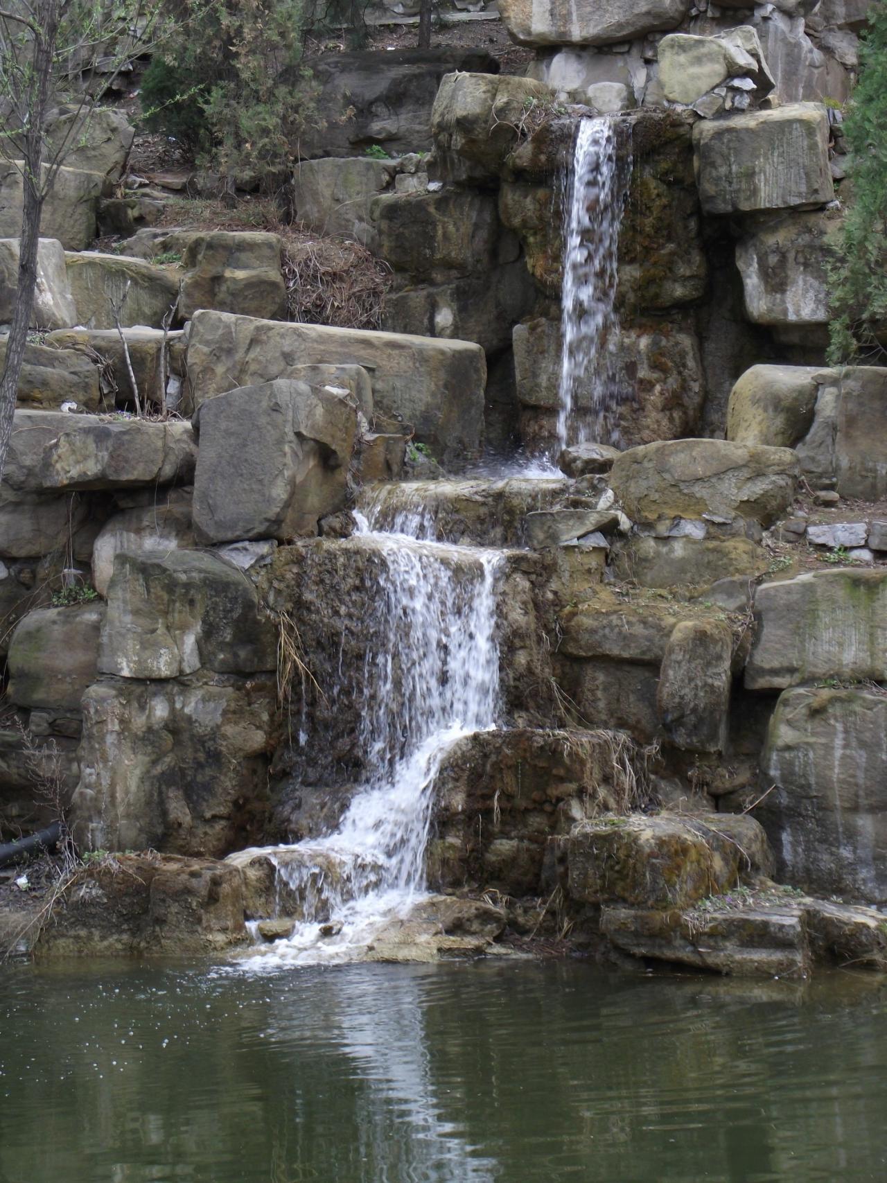 山涧岩石中流入碧绿湖面的泉水