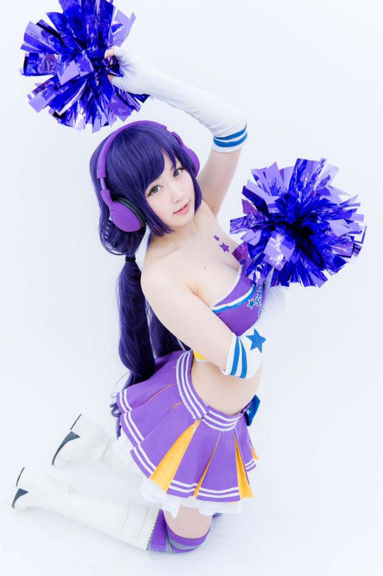 御伽ねこむ扮东条希左手举着拉拉队花球，右手拿着拉拉队花球放在胸前，侧身跪姿