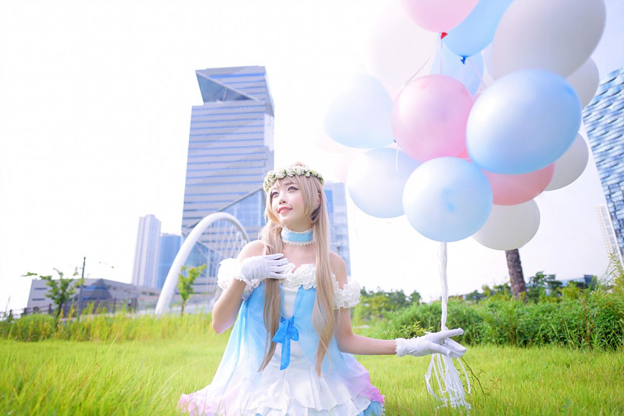兔娘tomia扮南小鸟右手拿着气球，左手放在胸前，右转头仰望天空